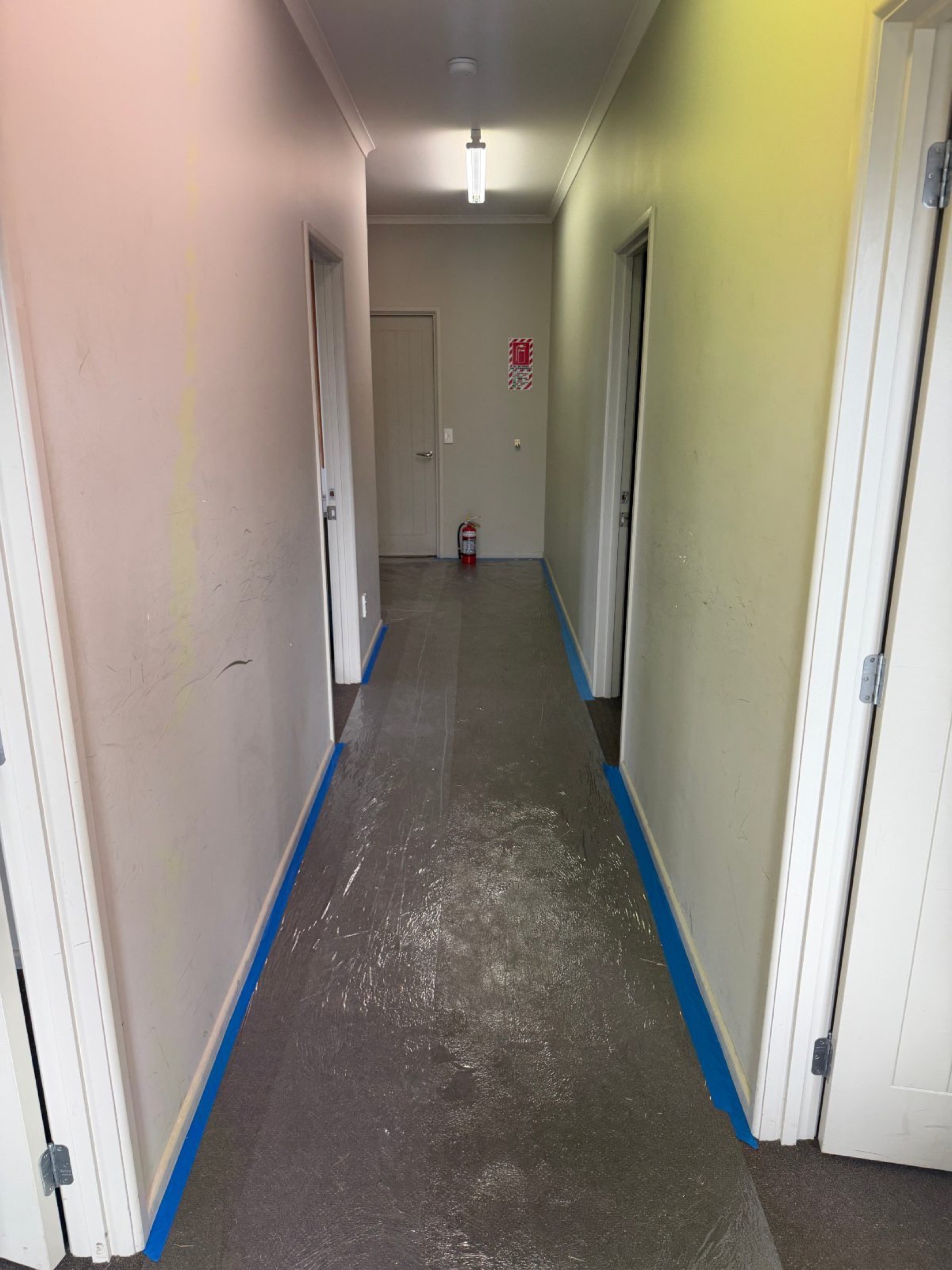 Interior hallway with scuffed walls and taped skirtings during preparation, before painting.